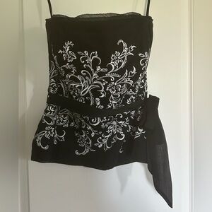 Strapless bustier with white embroidery and black tie at waist.